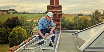 Man on roof installing PV Solar Panels